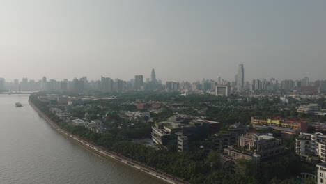 aerial of suburban houses next to the river looking at city skyline of guangzhou city, china