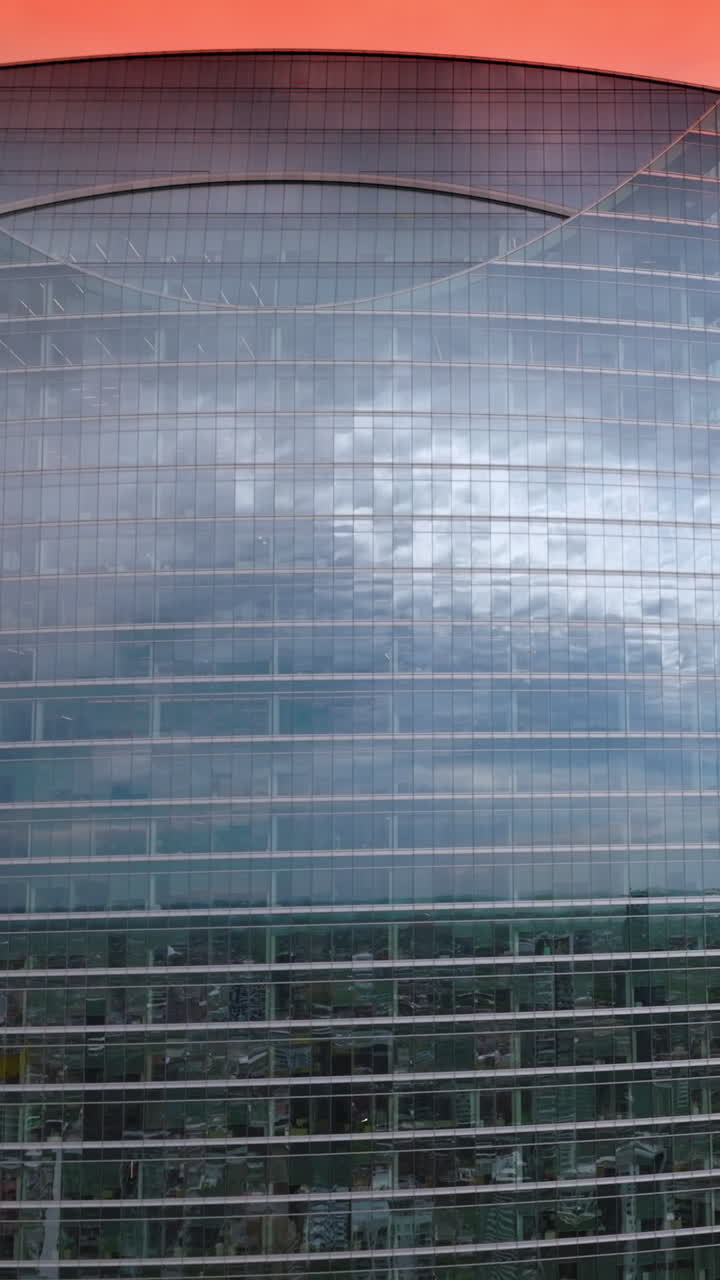 Cloudscape reflecting in the mirror windows of Chicago skyscrapers. High stunning buildings at the background of pink skies. Vertical video