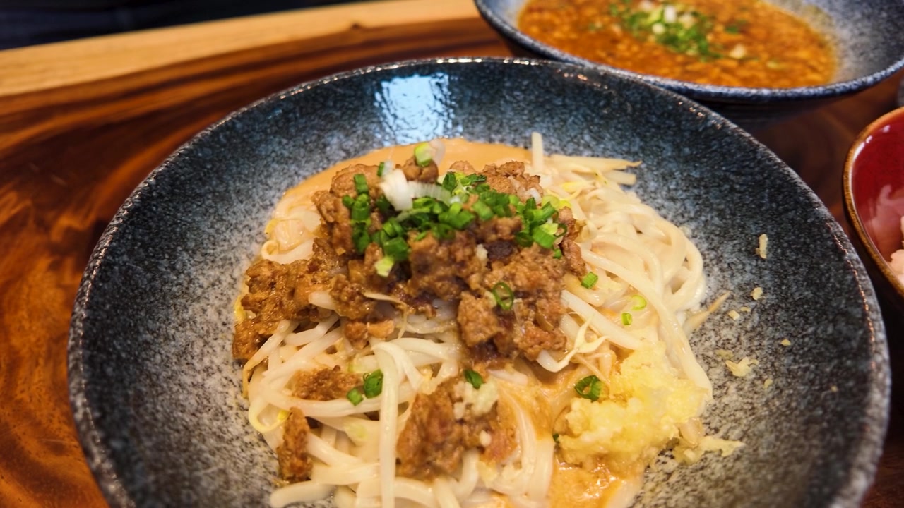 Primo piano di Ma Jiang Mian con carne di maiale macinata e aglio su un tavolo di legno.