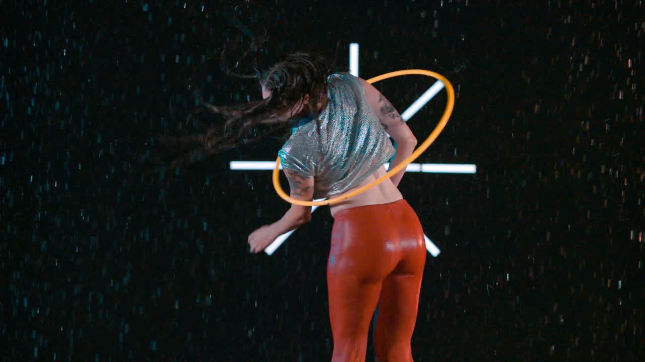 Amazing hula hooping skills, female hula hooper performing body workout in wet studio