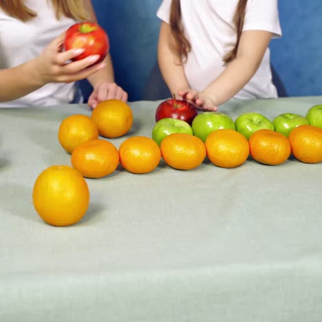 mother and daughter playing with fresh fruits at home. child and a female putting ripe fruits on the table. organic food concept.