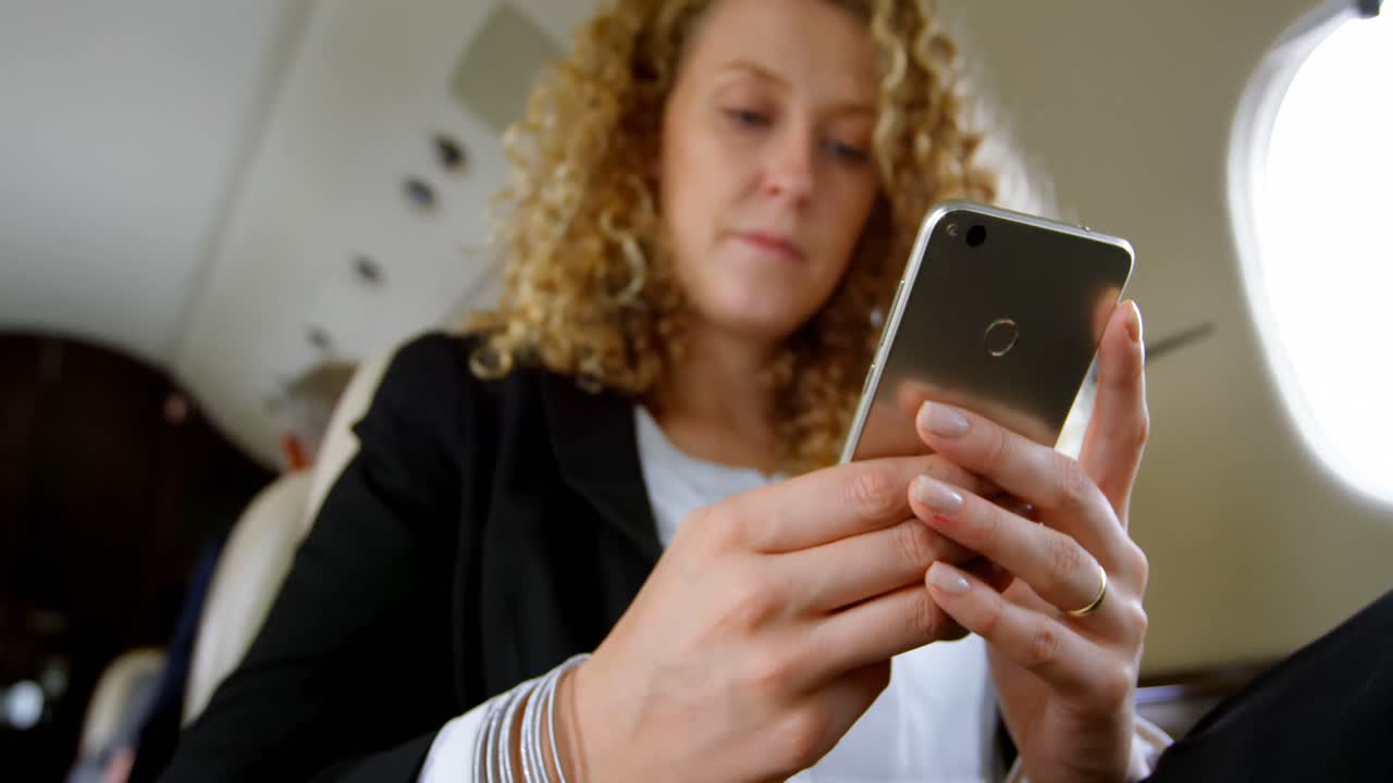 Donna d'affari che utilizza lo smartphone su jet privato 4k