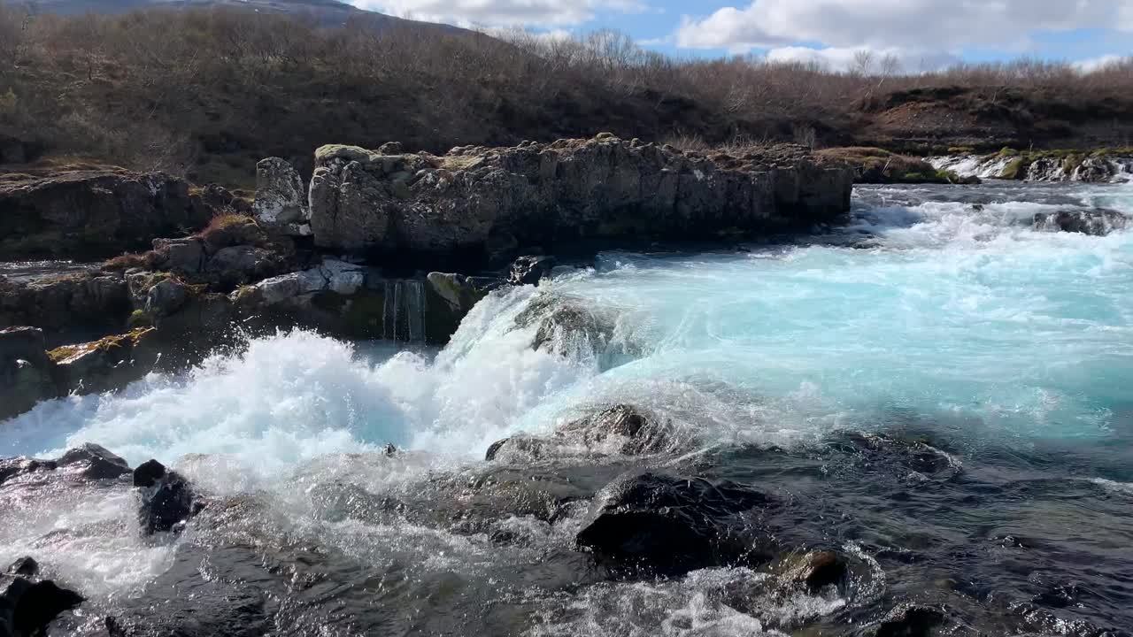 Zooming in on the beautiful waterfall Midfoss next to Bruarfoss with Icelands most turquoise water, watching the water pouring from the rocks and whirling around