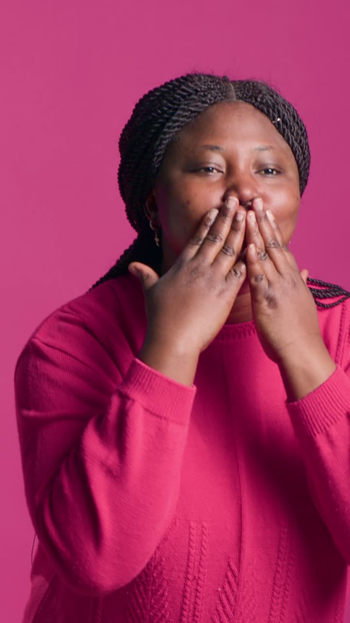 Ritratto di donna afroamericana che manda un bacio su sfondo rosa