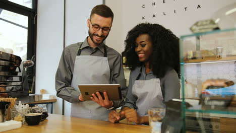 two young barista man and woman using tablet computer during a break in a coffee shop