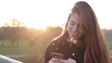 alternative millennial woman laughing and writing in her phone at sunset footbridge