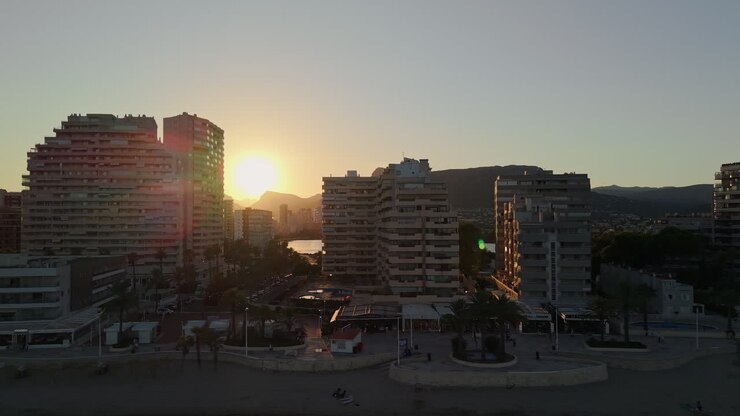 Pôr do Sol Dourado Sobre Cidade Costeira com Praia e Montanhas