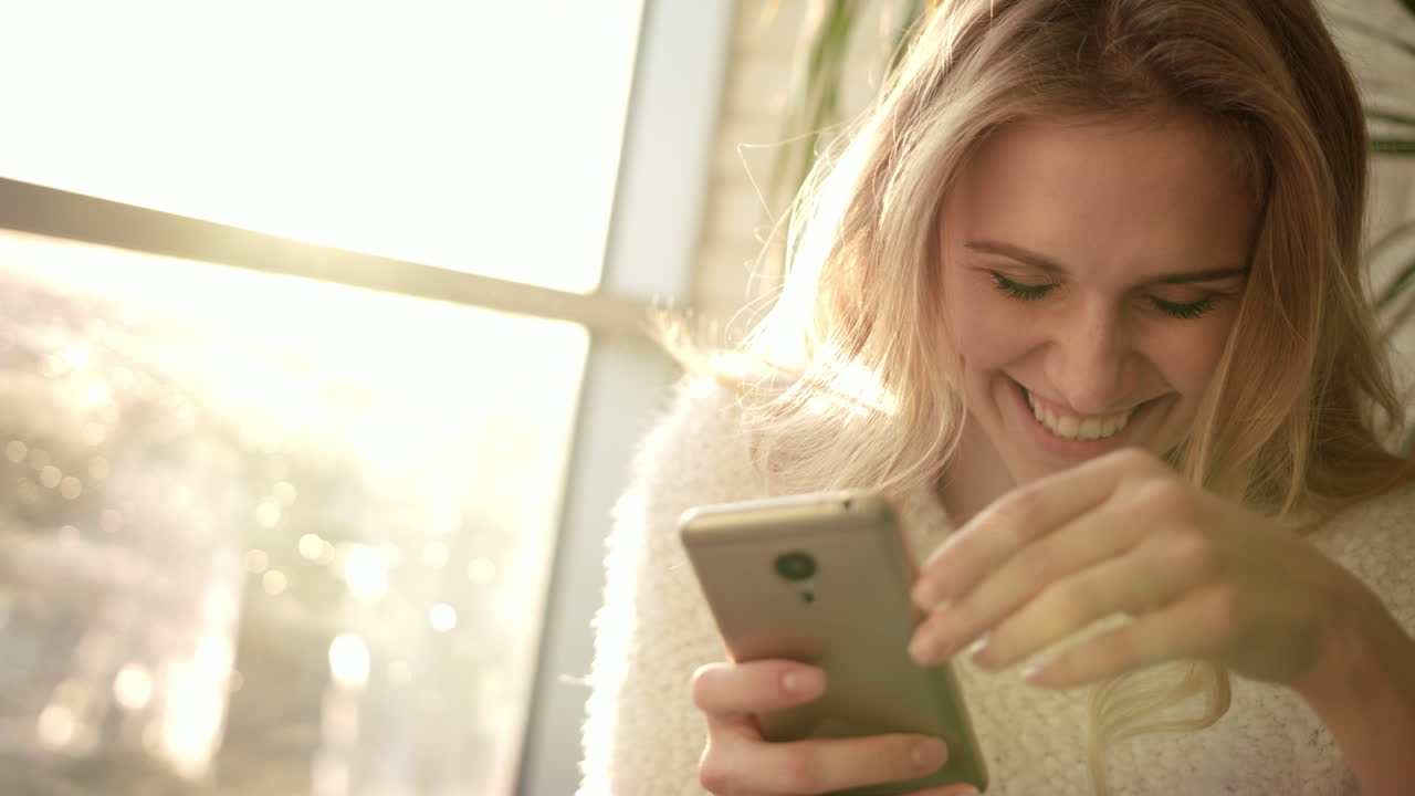 Donna sorridente che invia SMS sullo smartphone. Donna gioiosa che invia messaggi dal cellulare.