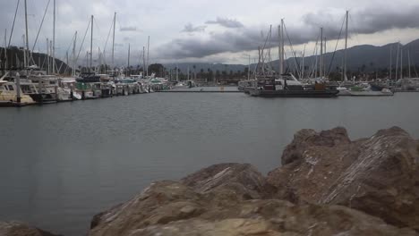 Camera-moving-above-rocks-showing-anchored-boats-in-a-harbor