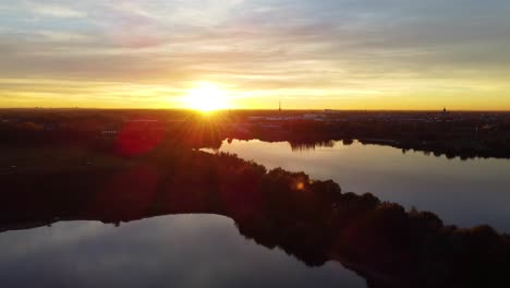 reflective lake water during golden sunset in belgium, aerial drone view