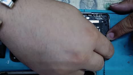 disparo de arriba hacia abajo de un componente de teléfono inteligente que se está reparando en una tienda