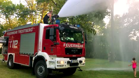 german firetruck spraying water for kids and trees on a hot summer day-8