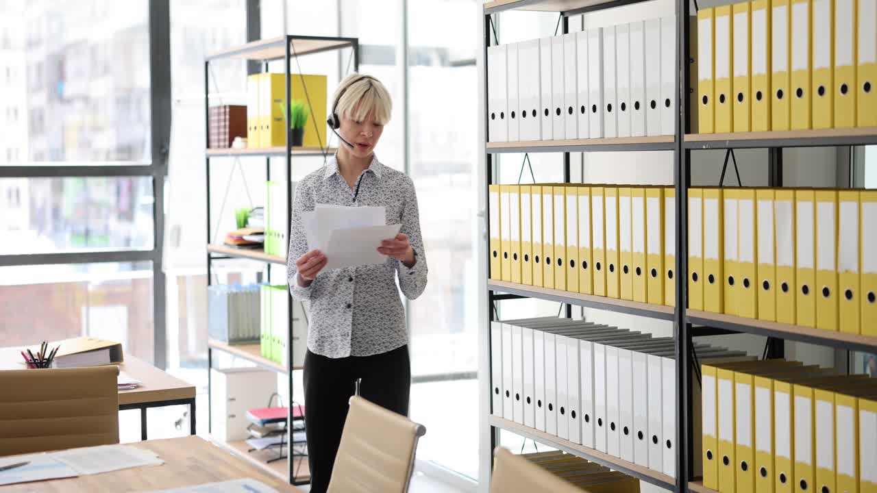 Woman reviewing documents in an office with file shelves