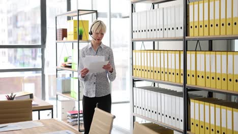woman reviewing documents in an office with file shelves