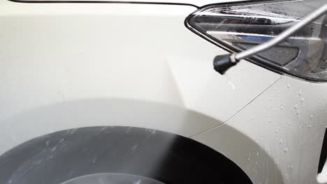 close-up of a white suv being sprayed by a pressure washer