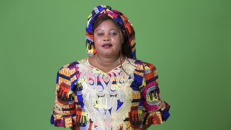 una hermosa mujer africana con sobrepeso que lleva ropa tradicional contra un fondo verde