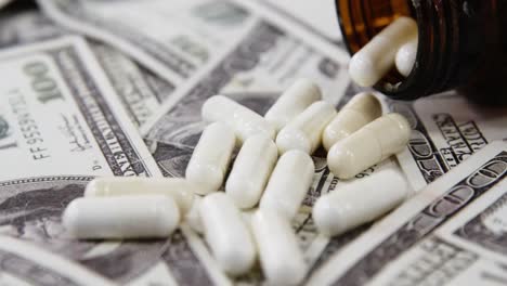 lots of dollar bank notes scattered with pills on table