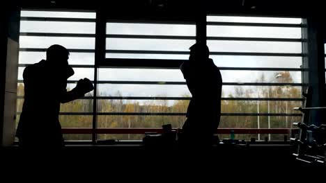 silhouette of two men boxing in a gym