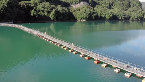 aerial orbiting shot of floating pontoon bridge in the middle of calm and peaceful turquoise waters of lake okutama in tokyo