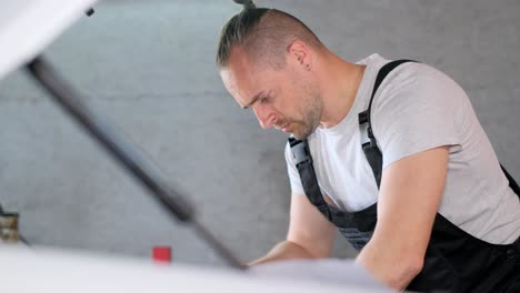 a man in overalls working on a car engine