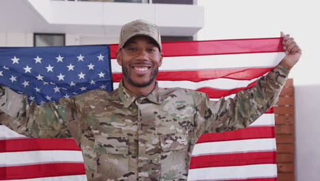 Un-Milenario-Soldado-Negro-Camina-Hacia-La-Cámara-Sosteniendo-Nuestra-Bandera,-Sonriendo-A-La-Cámara,-De-Cerca