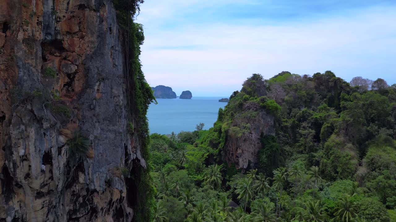 Breathtaking view of Railay beach from a cliff overlooking lush tropical jungle vegetation in Krabi, Thailand. Stunning aerial view flight fly reverse drone