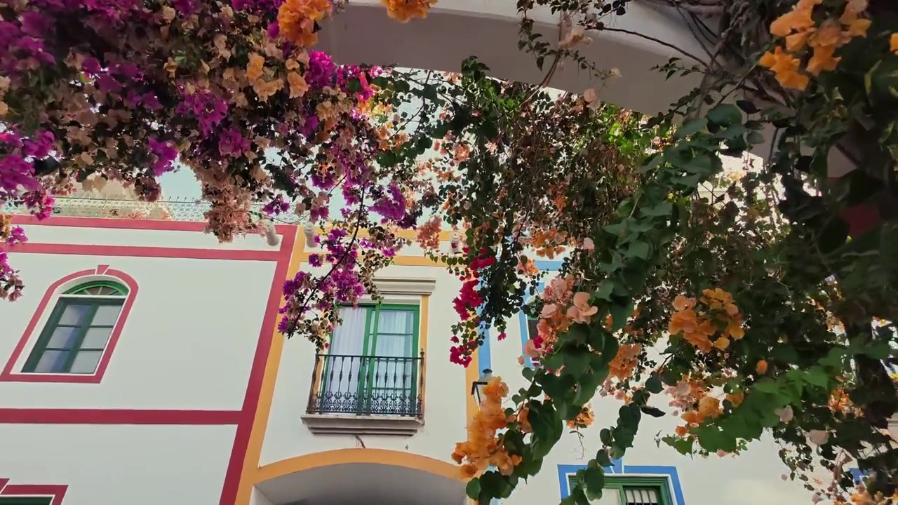 Rua pitoresca com casas brancas tradicionais e buganvílias coloridas em Puerto de Mogan, Gran Canaria, ao nascer do sol.