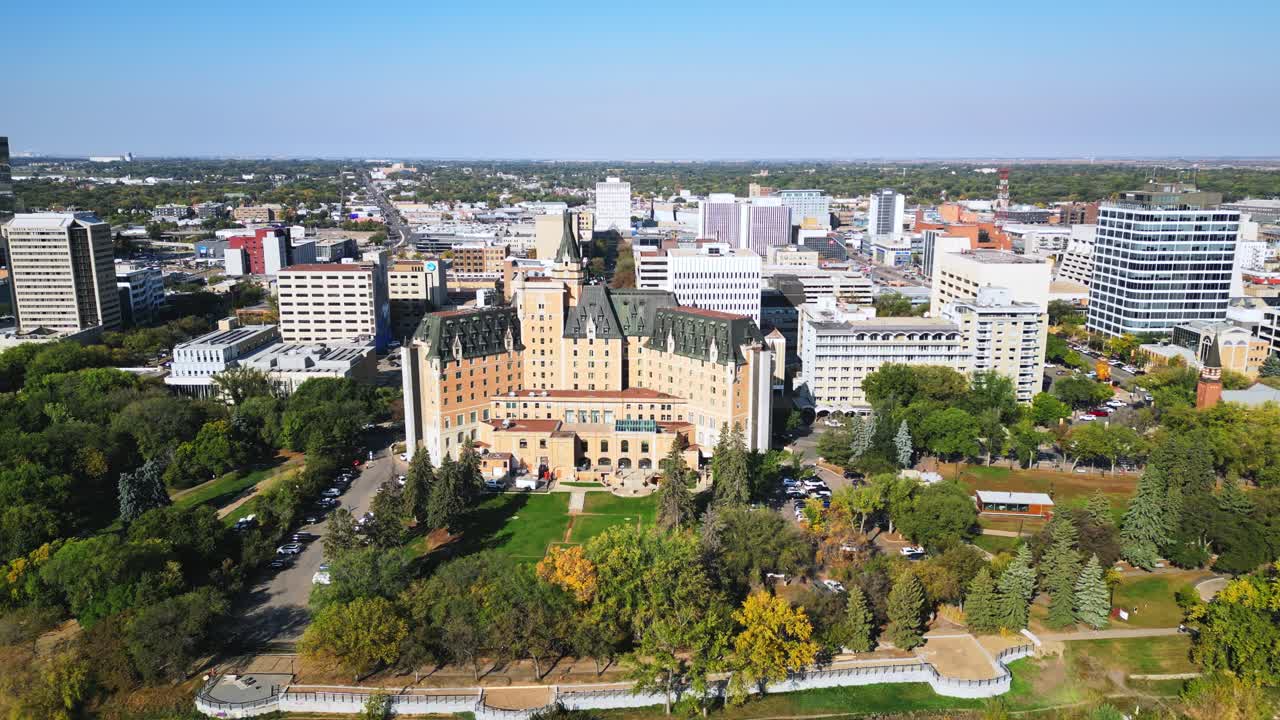 Slow drone shot shows large historic Saskatoon riverfront building in the fall