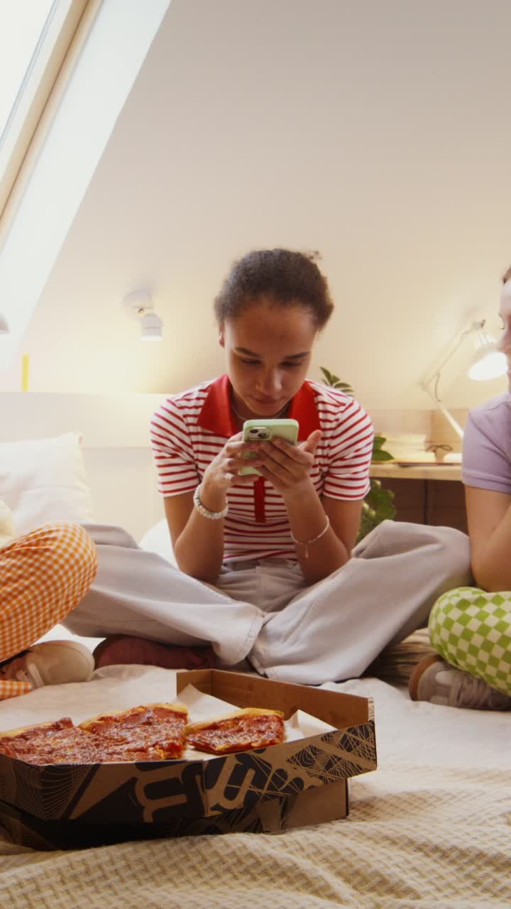 Teenage Friends Enjoying Pizza and Smartphones in a Bedroom