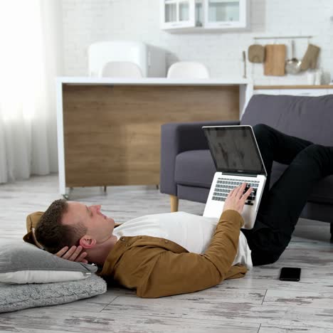 man lying on floor with laptop. young man working on laptop while lying onn floor