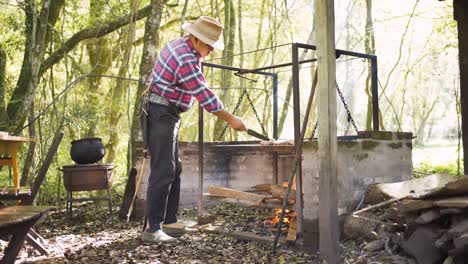 hombre étnico preparando trozos de carne cruda sobre un fuego ardiente
