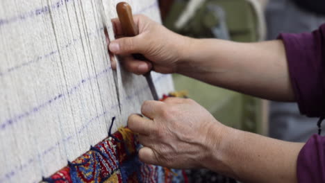 woman's hands using a knife to cut whilst weaving in turkey