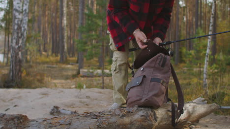 fisherman is opening his backpack with fishing equipment in forest closeup view relax and calmness at nature