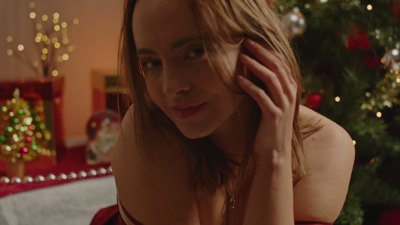 A sexy woman wearing a velvet nightdress sensually plays with her hair while seductively looking at the camera