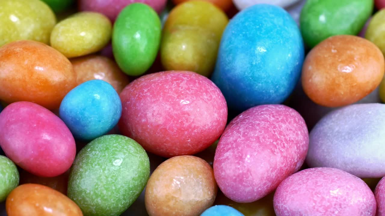 Pila di molti confetti rotondi e gommosi con glassa multicolore che ruotano lentamente su un piatto girevole