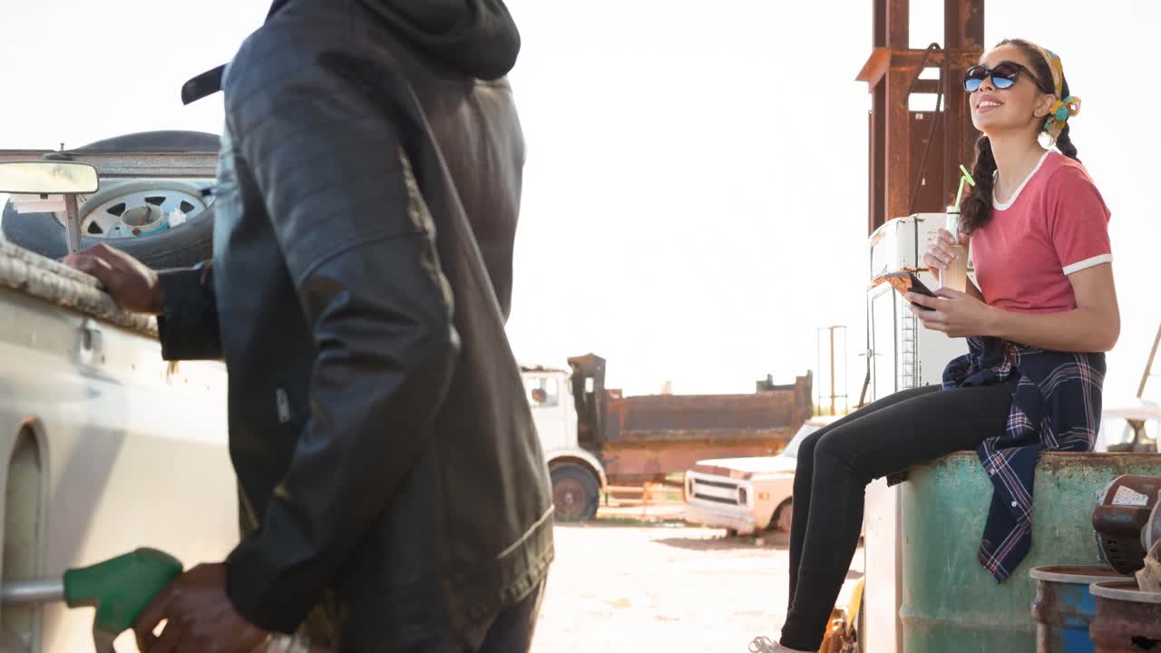 연료  ⁇ 프를 사용하여 웃는 다양한 남자와 여자가 주유소에서 트럭을 채우고 있습니다.