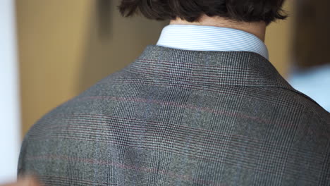 showing hem of tweed suit jacket collar on boutique customer, close up