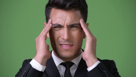 young handsome hispanic businessman against green background
