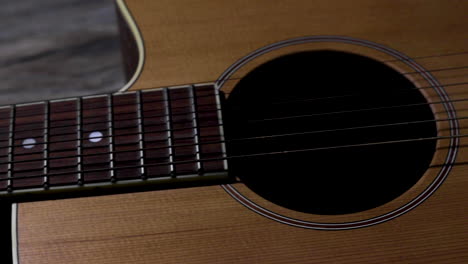 moving slider shot from left to right of an acoustic guitar from the fret board to the bridge