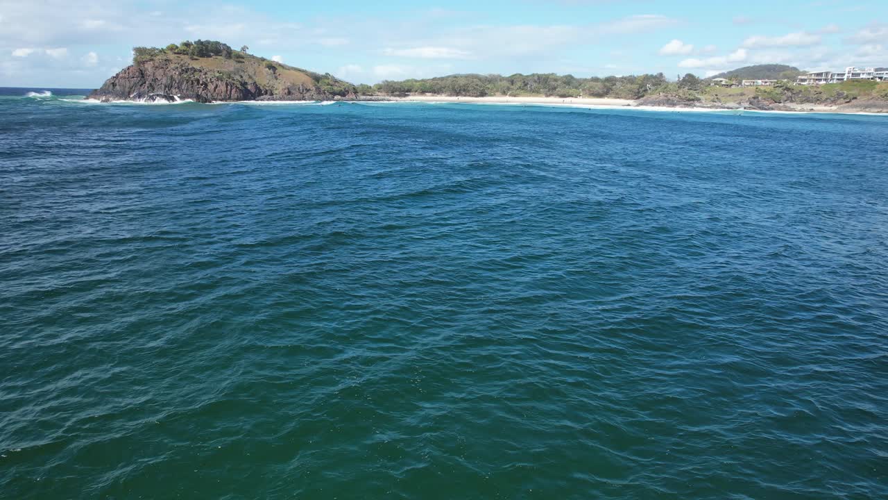 Promontorio di Norries e delfini tursiopi che nuotano nell'oceano nel Nuovo Galles del Sud, Australia - ripresa aerea in allontanamento