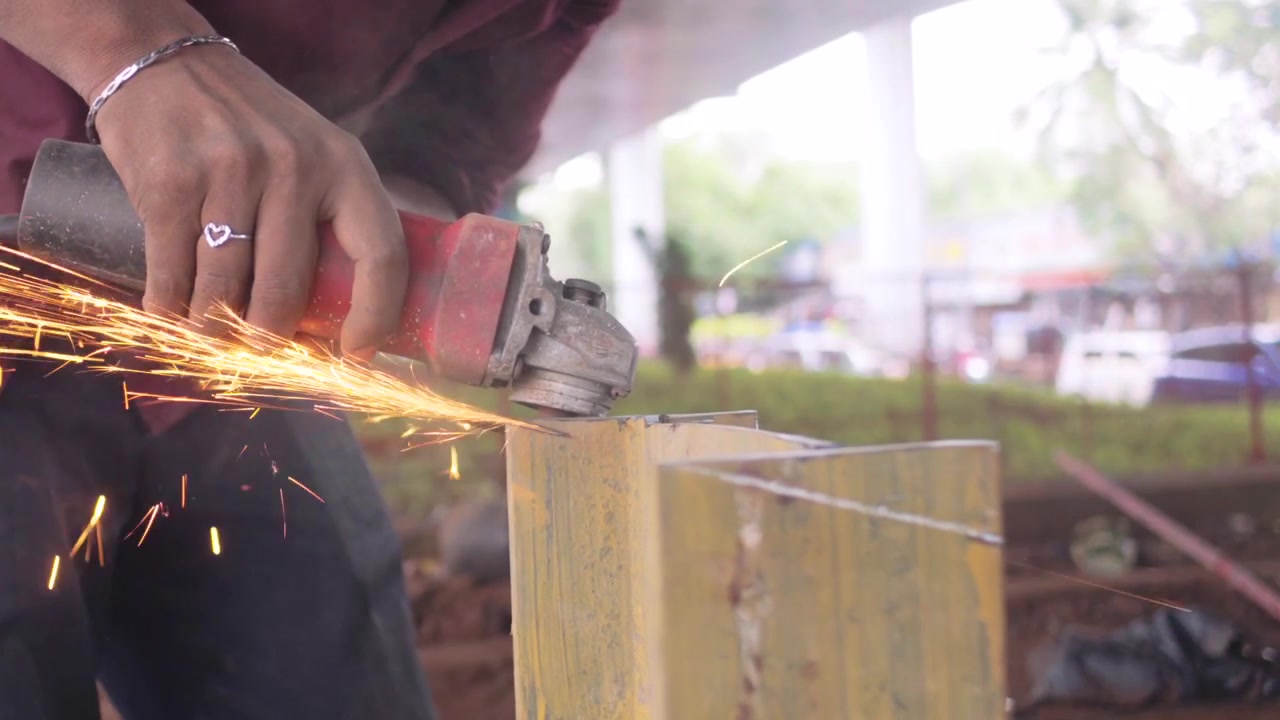 He is cutting a large iron rod with a grinding machine closeup view