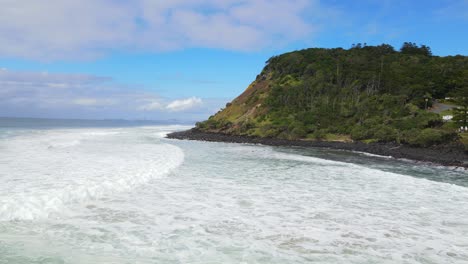 Olas-Espumosas-Salpicando-A-Los-Pies-Del-Parque-Nacional-Burleigh-Head-Con-Edificio-De-Apartamentos-Cerca-Del-Mirador-Jebbribillum