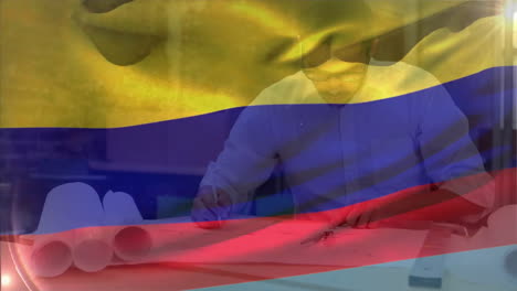 animation of flag of colombia waving over smiling caucasian male architect working on blueprint