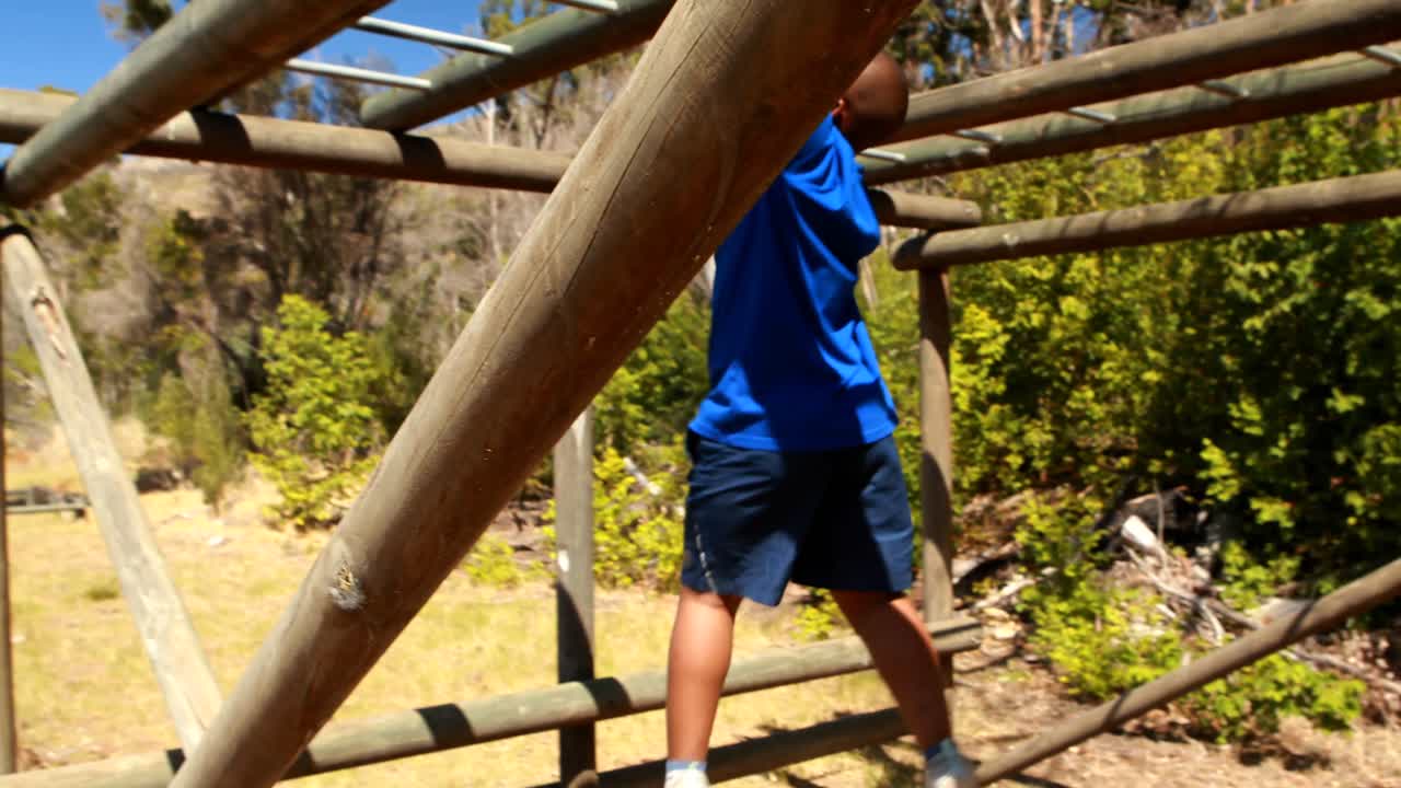 Determined boy exercising on monkey bar during obstacle course