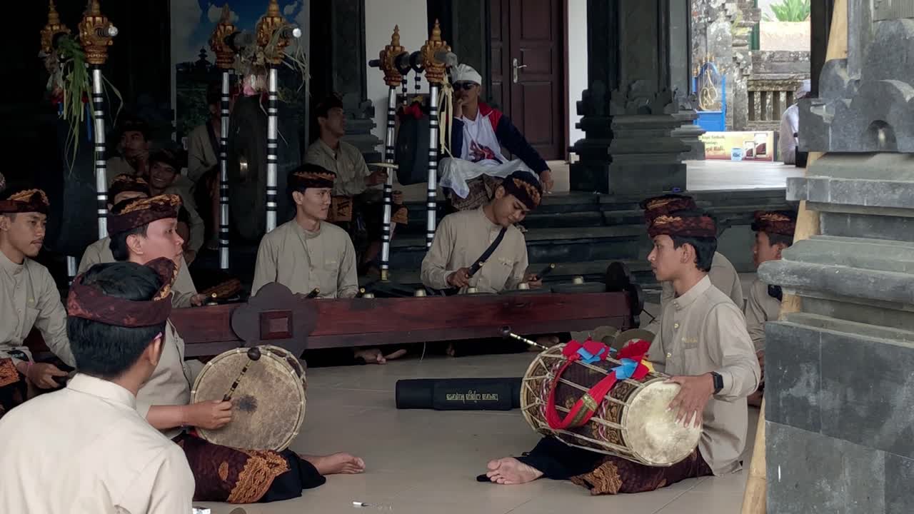 Group of Asian men in religious wardrobe making music in a Hindu temple in Bali, Indonesia