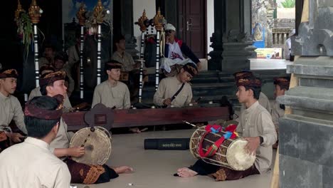 group of asian men in religious wardrobe making music in a hindu temple in bali, indonesia