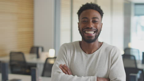 portrait of young businessman walking into focus in modern open plan office