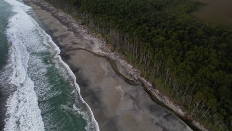 foamy ocean waves splashing shore at maori beach in south island, new zealand - drone shot