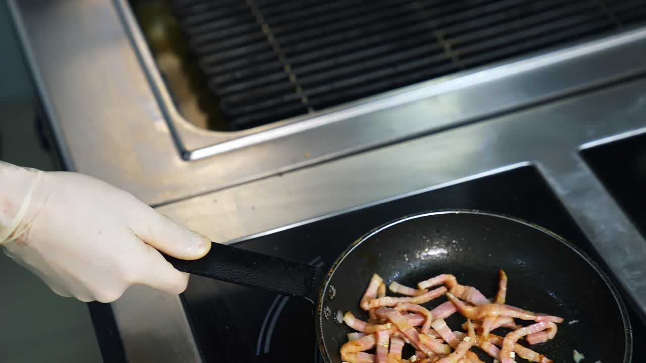 Cooking bacon for breakfast. Chef turns crispy bacon in frying pan. Ingredients for burger. Close up.