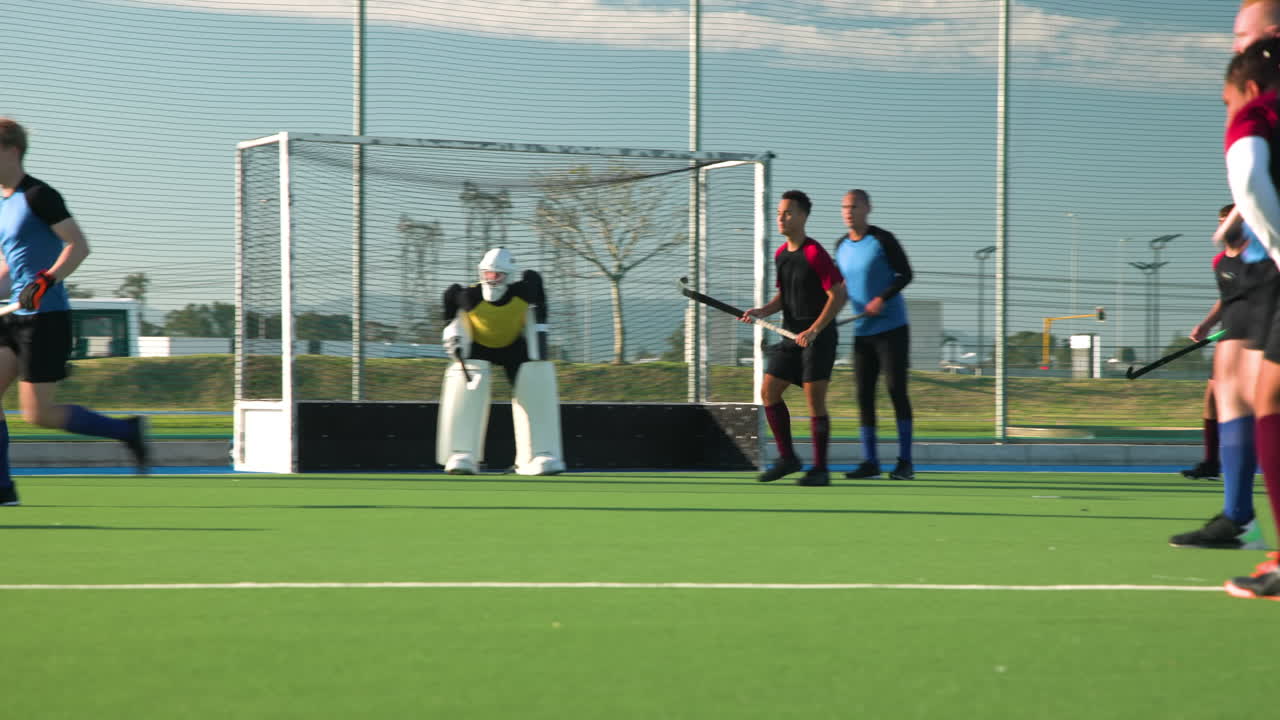Playing field hockey, male players competing in outdoor match, focusing on game